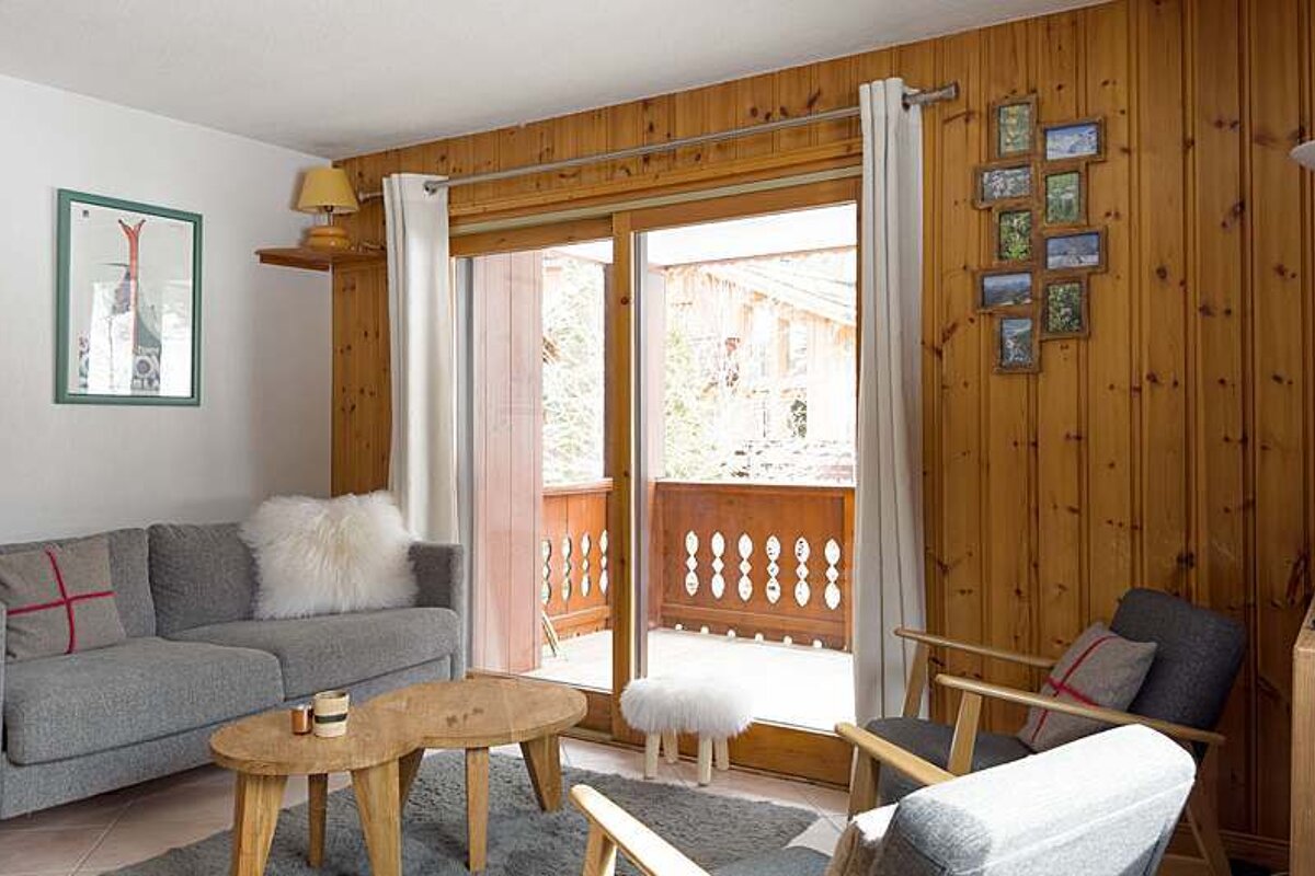 A living room with a couch and chairs and a balcony