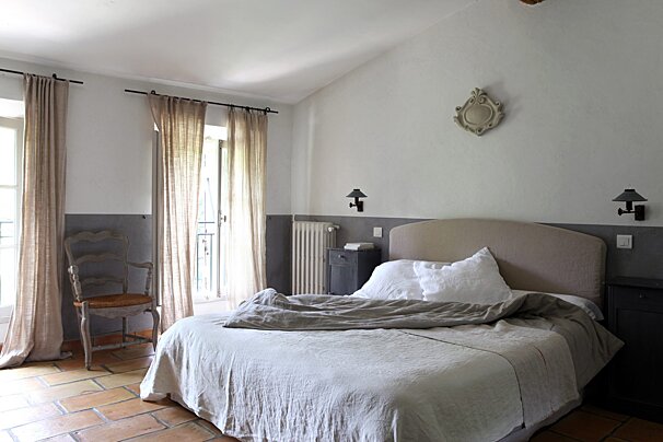 A bedroom with a large bed and a chair