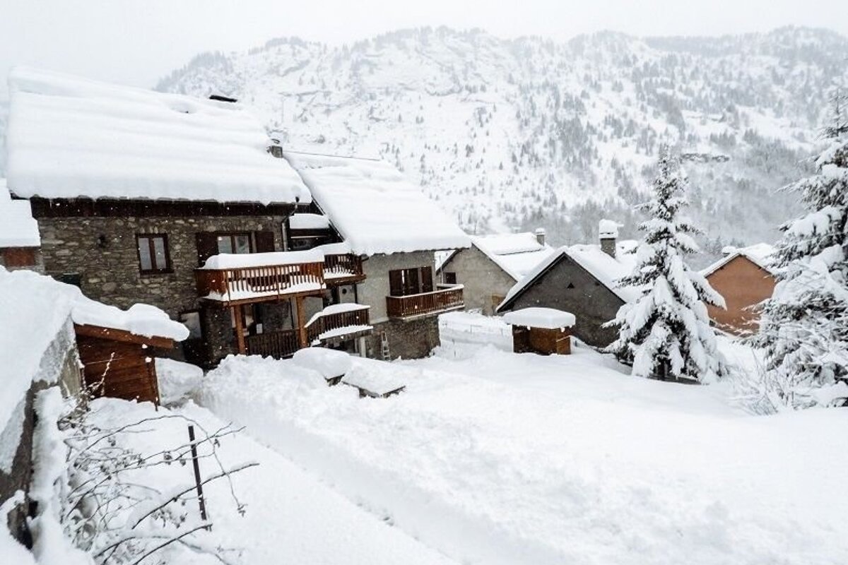A snowy landscape with houses and trees covered in snow