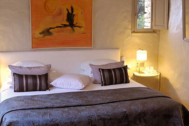 Double bed with silver through and orange painting above bed