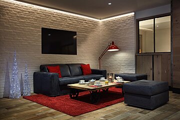 A living room with a black couch and red pillows