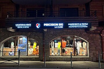 A precision ski store is lit up at night