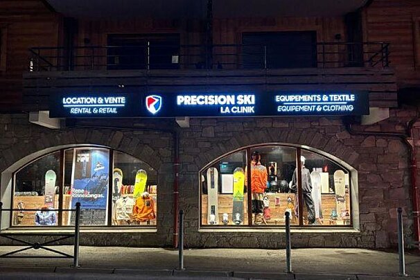 A precision ski store is lit up at night
