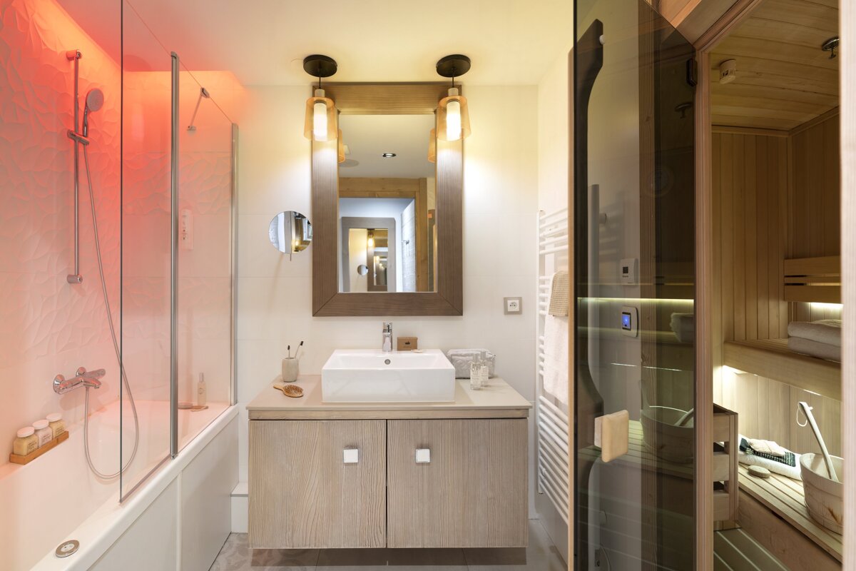 A bathroom with a sink and a sauna in the background