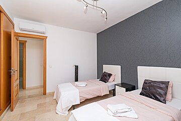 A bedroom with two beds and a gray wall