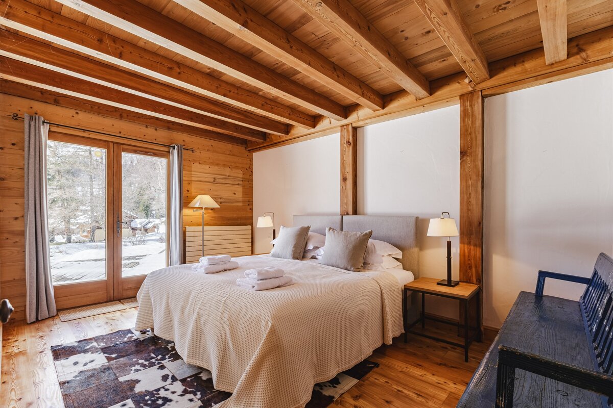 A bedroom with a wooden ceiling and a large bed
