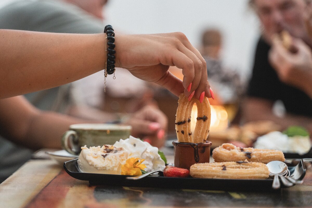 A woman wearing a bracelet reaches for a churro