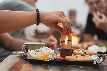 A woman wearing a bracelet reaches for a churro