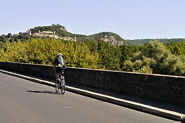 a cyclist on a bridge over the dordogne