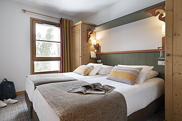 A hotel room with two beds and a magazine on the bed