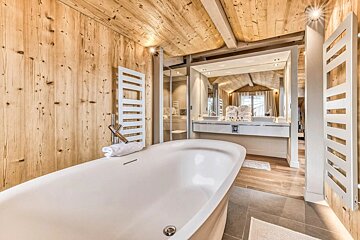 A bathtub in a bathroom with wooden walls