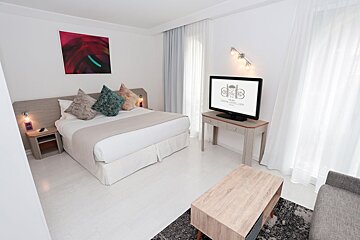 A hotel room with a king size bed and a flat screen tv