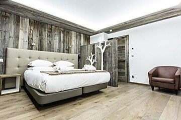 A hotel room with a large bed and a chair