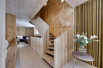A wooden staircase with a vase of flowers on a table