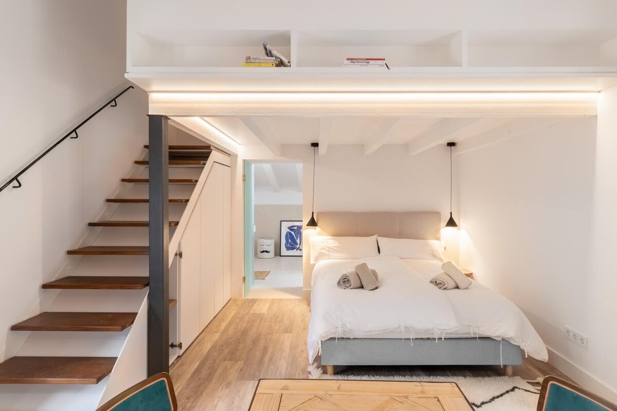 A bedroom with a bed and stairs leading up to it