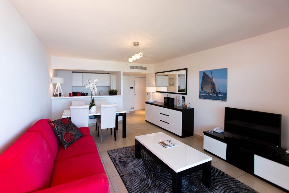 A living room with a red couch and a picture of a sailboat on the wall