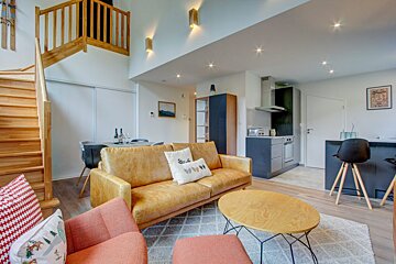 A living room with a couch and stairs leading up to the second floor