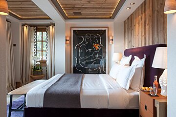 A bedroom with a large painting on the wall above the bed