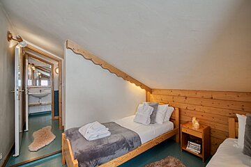 A bedroom with two beds and a nightstand with books on it