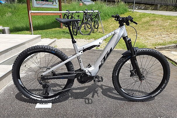 A bicycle is parked in front of a sign that says brun sports