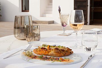 A plate of food sits on a table next to a glass of wine