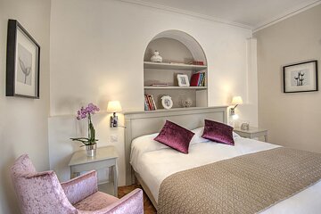 A bedroom with a bed purple pillows and a chair