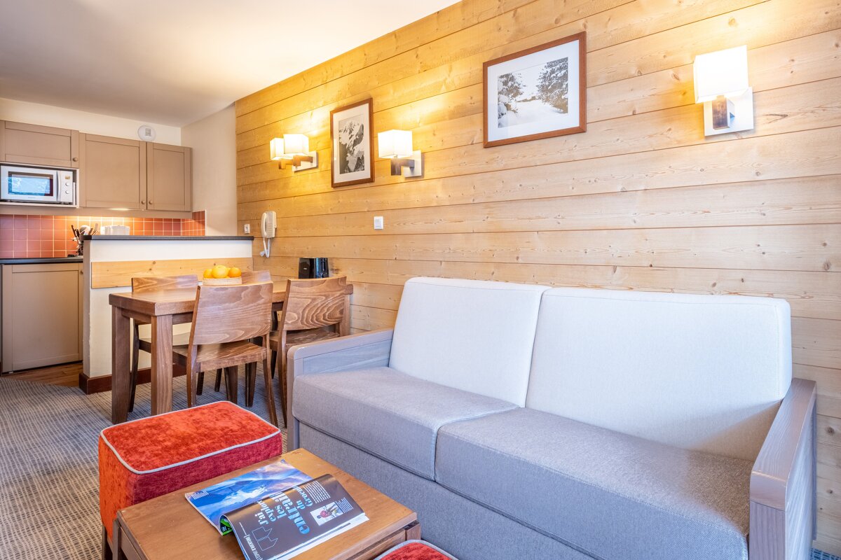 A living room with a couch a table and chairs and a book on the table that says ' altitude ' on it