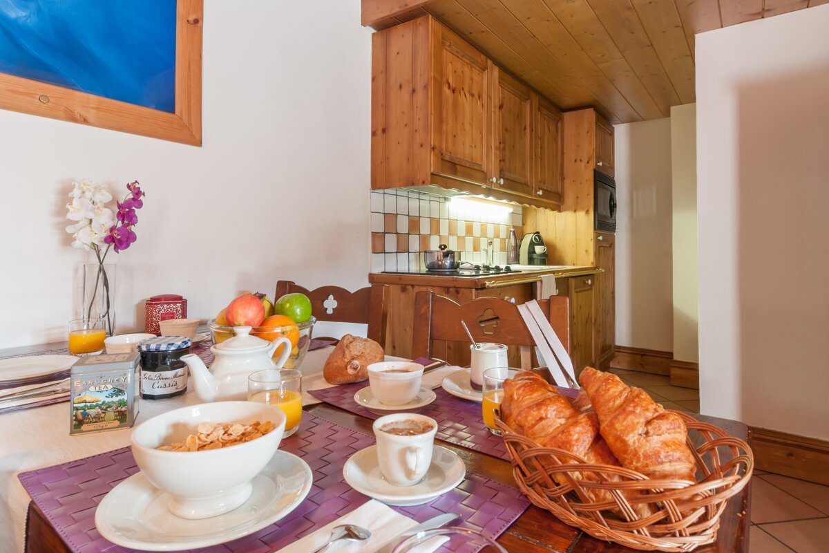 A bowl of cereal sits on a table next to a basket of croissants
