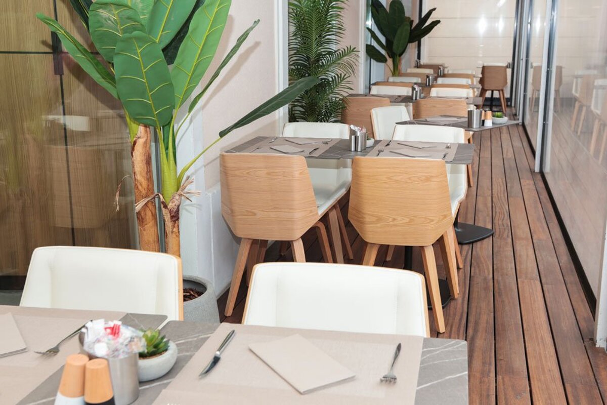 A restaurant with white chairs and wooden tables