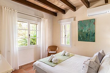 A bedroom with a painting on the wall above the bed