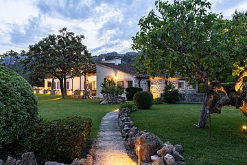 A stone walkway leading to a house with lights on
