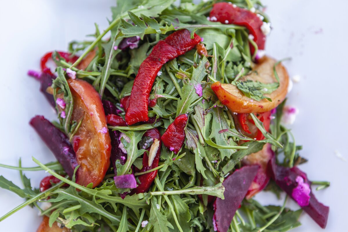 A salad with red peppers and tomatoes on a white plate