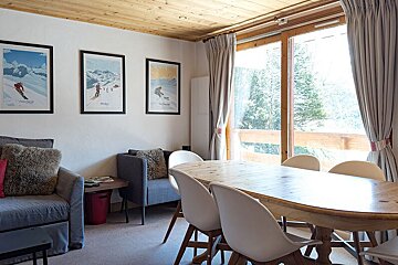 A living room with a dining table and chairs and three posters on the wall