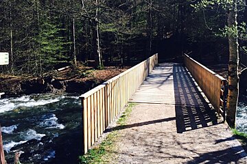 a bridge over a river with trail marker signs