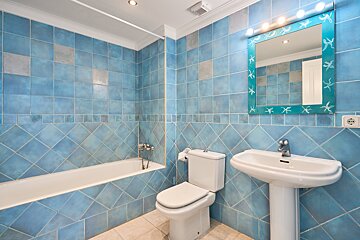 A bathroom with blue tiles and a blue starfish mirror