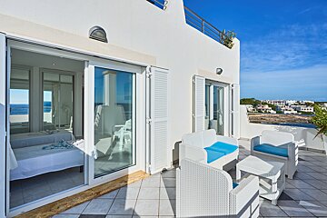 A balcony with white furniture and a view of the ocean