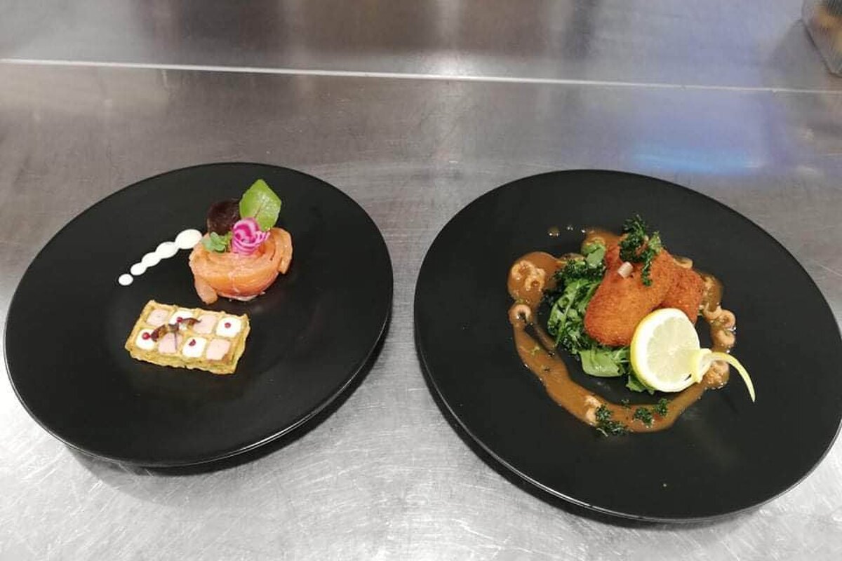 Two black plates with food on them on a counter