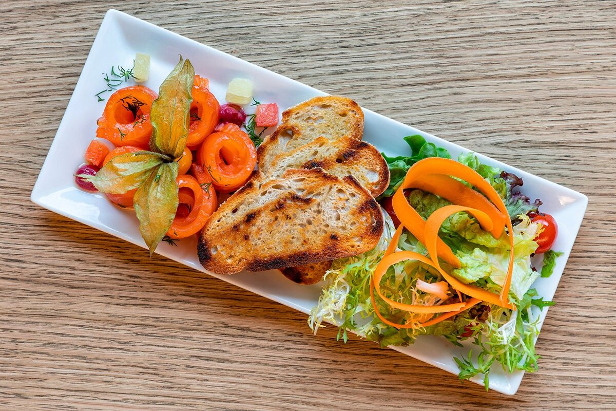 A plate of food with bread and vegetables on a wooden table