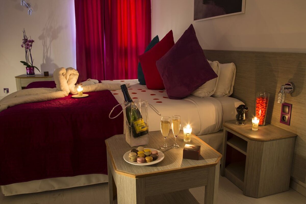 A bottle of champagne sits on a table in front of a bed