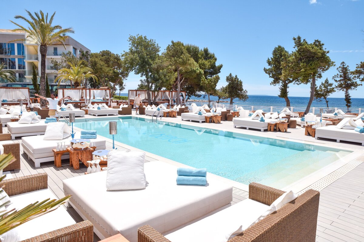 A man stands in front of a large swimming pool that says ' ibiza ' on it