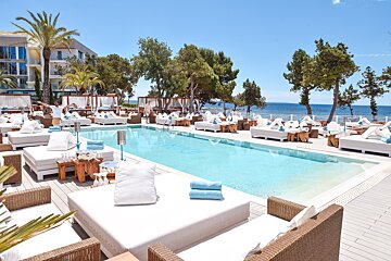 A man stands in front of a large swimming pool that says ' ibiza ' on it