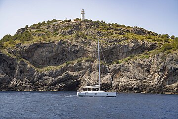 A sailboat in the water with a lighthouse in the background