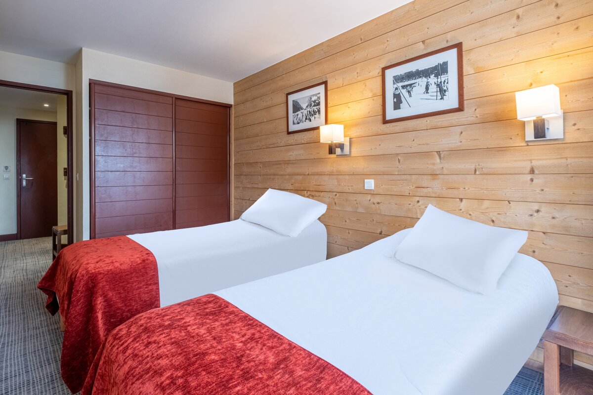 A hotel room with two beds and two pictures on the wall