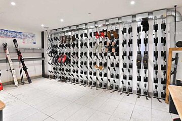 Several pairs of atomic skis are lined up against a wall