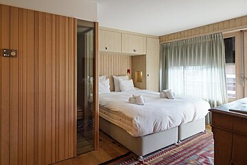A bedroom with a dresser and a bed with white sheets
