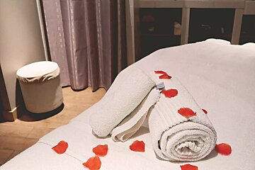 A bed with towels and rose petals on it