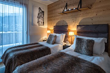 A bedroom with two beds and a picture of a wolf on the wall
