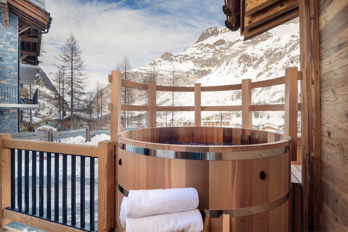 A wooden hot tub with a mountain in the background