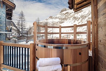 A wooden hot tub with a mountain in the background