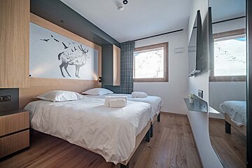 A bedroom with two beds and a tv on the wall